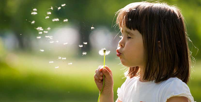 Girl blowing on dandilion